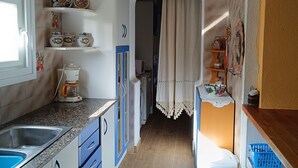 A kitchen with a sink, blue cabinets, a coffee maker, and a window. - Villa Teresa (L´Ametlla de Mar)