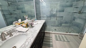 A modern bathroom with a glass shower enclosure, marble countertops, and a built-in sink.