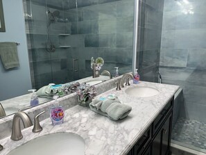 Un baño con dos lavamanos, una cabina de ducha de vidrio y un espejo grande.