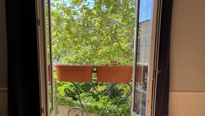 En skjutdörr i glas som leder ut till en balkong med krukväxter och utsikt över grönområden.
