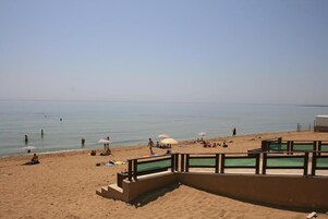 Una playa con una orilla arenosa, una zona de piscina y algunas sombrillas.