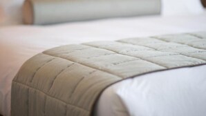 A neatly made bed with a quilted headboard and a white pillow. - Hotel Noto Marina Vista Mare (Noto)