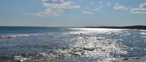 A beach with clear skies and sunlight reflecting on the water.