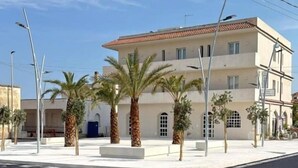 A multi-story building with a flat roof, palm trees, and a clear sky. - Hotel Noto Marina Vista Mare (Noto)