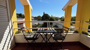 Un balcón con una mesa y dos sillas, con vista a una zona residencial con casas y árboles.