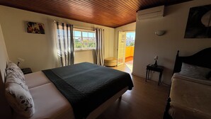 A bedroom with a bed, a nightstand, an air conditioning unit, a lamp, and a view of the outside. - Relaxing 5-Bedroom Villa with Private Pool, Outdoor Playground, Barbeque zona.

 (Carcavelos)