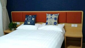 A bed with two pillows, a nightstand, and a wall with a blue and orange headboard.