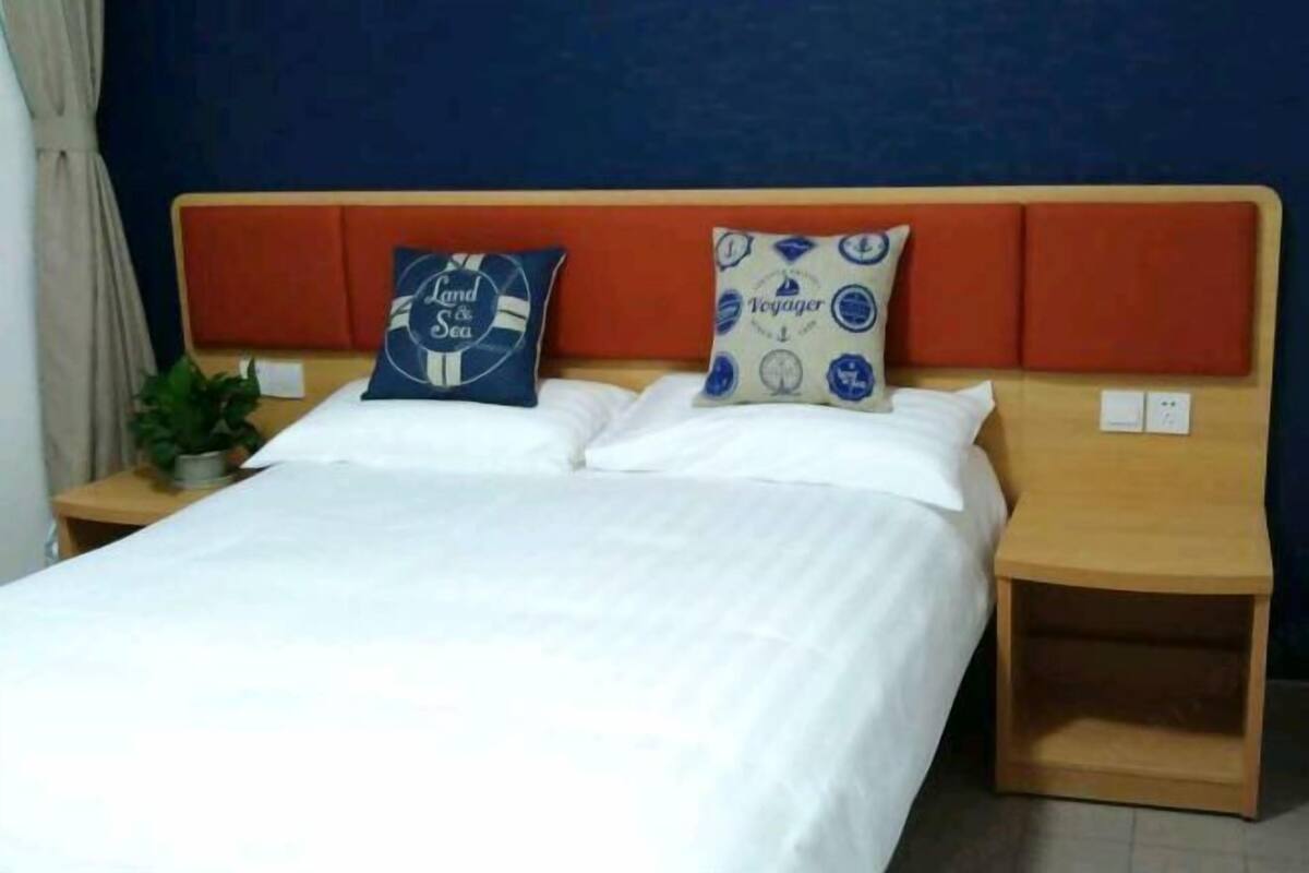 A bed with two pillows, a nightstand, and a wall with a blue and orange headboard.