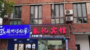 A building with a blue sign for Lanzhou Beef Noodles and a red sign for Spring Festival Inn.