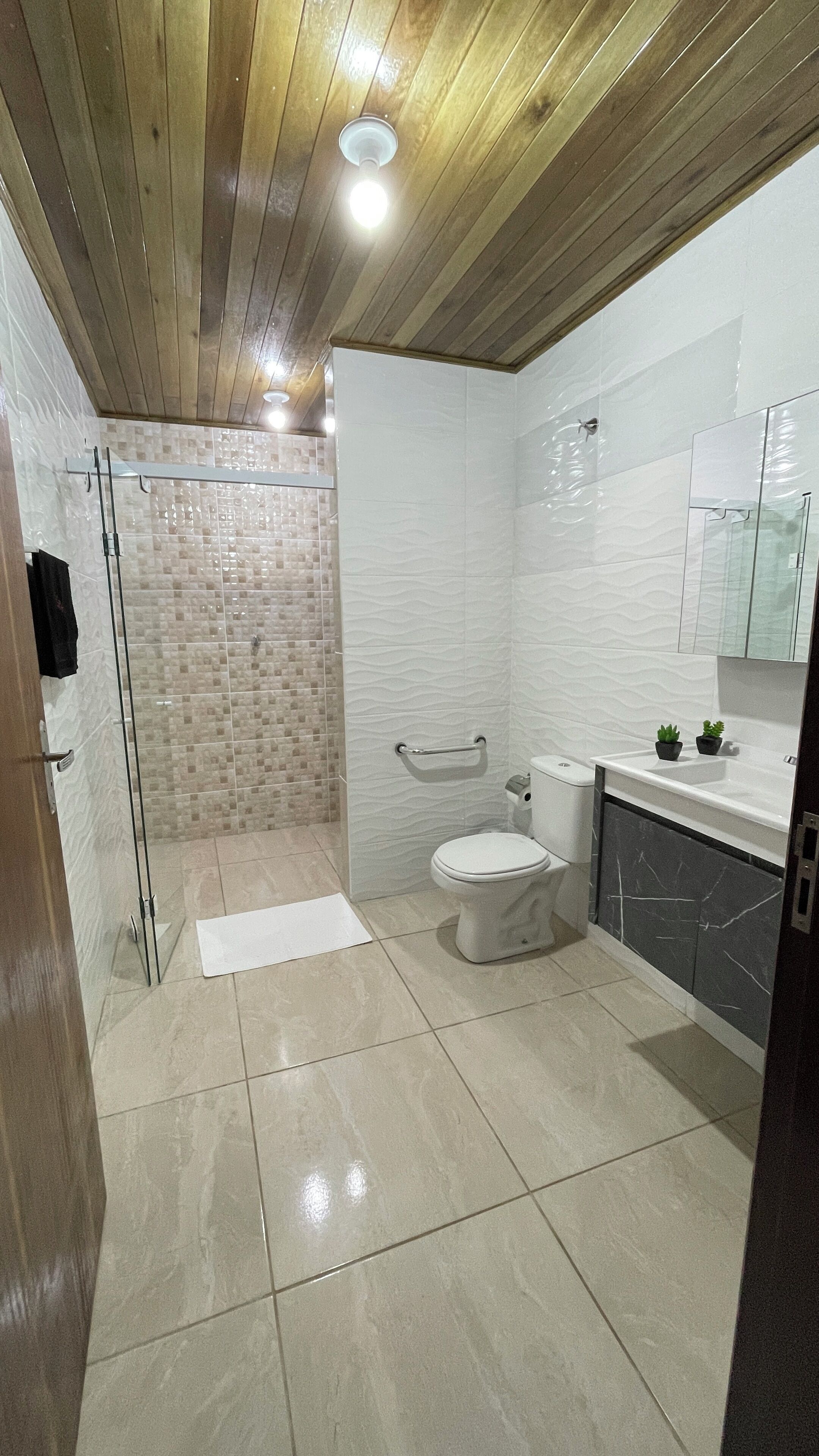 Ein modernes Badezimmer mit Duschkabine aus Glas, Toilette und Waschbecken mit Marmorplatte.