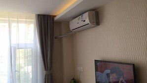 A room with a window, curtains, an air conditioning unit mounted on the wall, and a television on the opposite wall. - Dongyue Xiaozhu Hotel (Lanzhou University of Finance and Economics Yuchikou) (Lanzhou)