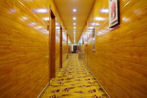 Un couloir aux murs en bois et au tapis à motifs, qui mène à une porte au fond.