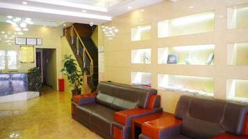 A lobby with a reception desk, a staircase, and seating areas.