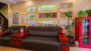 A lobby with a sofa, shelves with plants, a staircase, and a red decorative item. - Dongyue Xiaozhu Hotel (Lanzhou University of Finance and Economics Yuchikou) (Lanzhou)