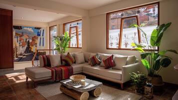 A living room with a sectional sofa, a coffee table, and large windows with a view of buildings.