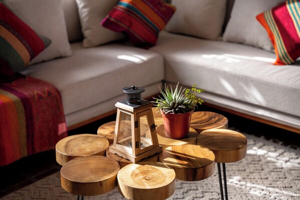 A living room with a sofa, colorful pillows, a wooden side table with a lantern, and a potted plant. - Cavana Hotel Boutique Cusco (Cusco)