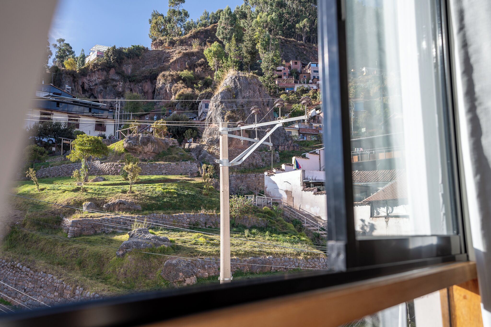 Vista d'una zona muntanyosa amb un camí de pedra, un edifici petit i una gran formació rocosa.
