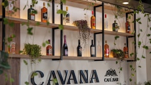 A bar named CAVANA with shelves of liquor bottles and decorative plants. - Cavana Hotel Boutique Cusco (Cusco)