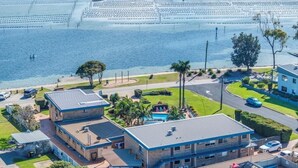 A residential area with a swimming pool, multiple houses, and a beachfront. - Lakeside Apartments - Ground floor (Merimbula)