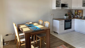 A compact kitchen with white cabinets, a built-in oven, and a microwave. - Cozy family apartment in the heart of Görlitz, also suitable for fitters (Görlitz)