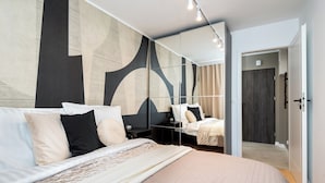 Une chambre à coucher moderne avec un grand lit, une table de chevet, un miroir et une armoire.