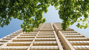 Un immeuble de grande hauteur avec une façade composée d’une grille de fenêtres et de balcons.