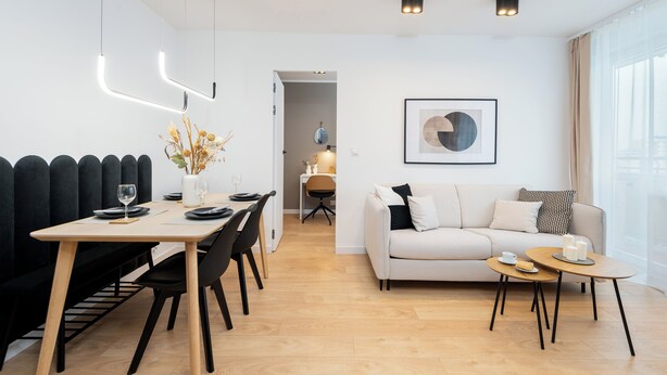 Un salon moderne comprenant un canapé, une table basse et un coin repas avec des chaises et une table.