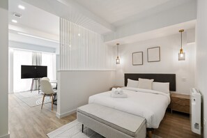 Une chambre d’hôtel moderne avec un grand lit, des tables de chevet, un bureau avec une chaise et un téléviseur.