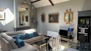 En moderne stue med sofa, sofabord, fjernsyn og et indbygget ovn.