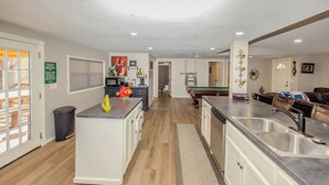 A modern kitchen with a central island, a dining area with a pool table, and a living room with a sofa and a coffee table. - Spacious 6-bedroom house in enjoyable PK with Waterfront Access Near Rocker-B (Graford)
