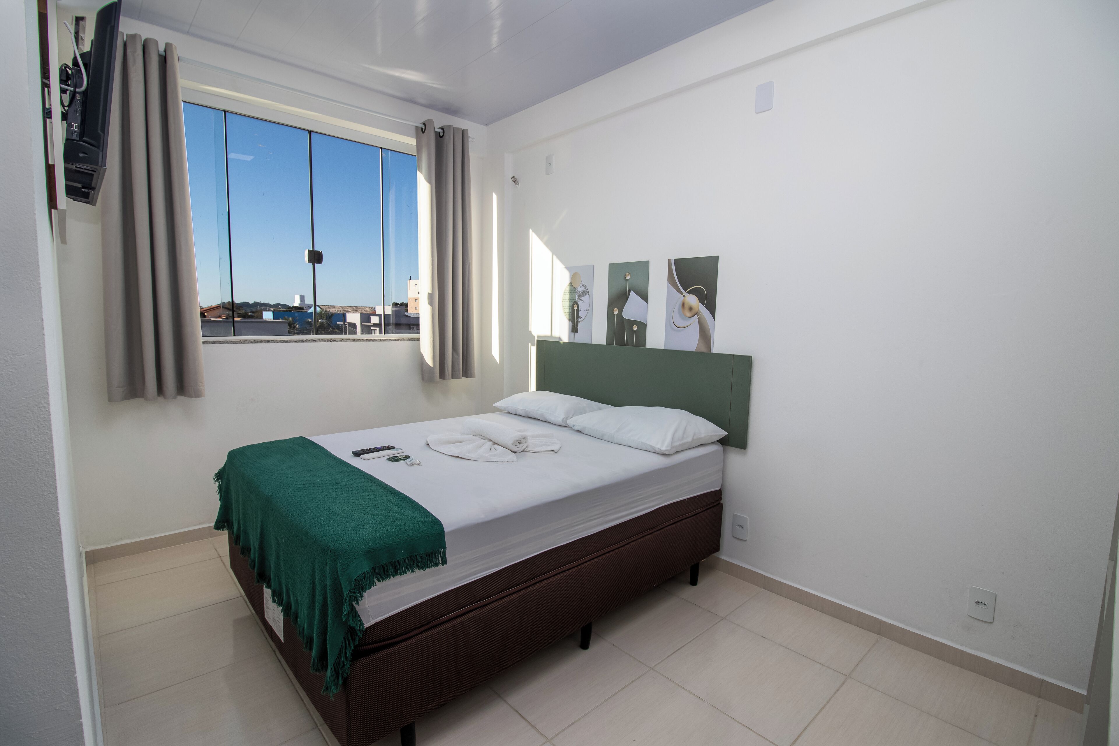 Una camera da letto con un letto, una finestra con tende e opere d'arte alle pareti.