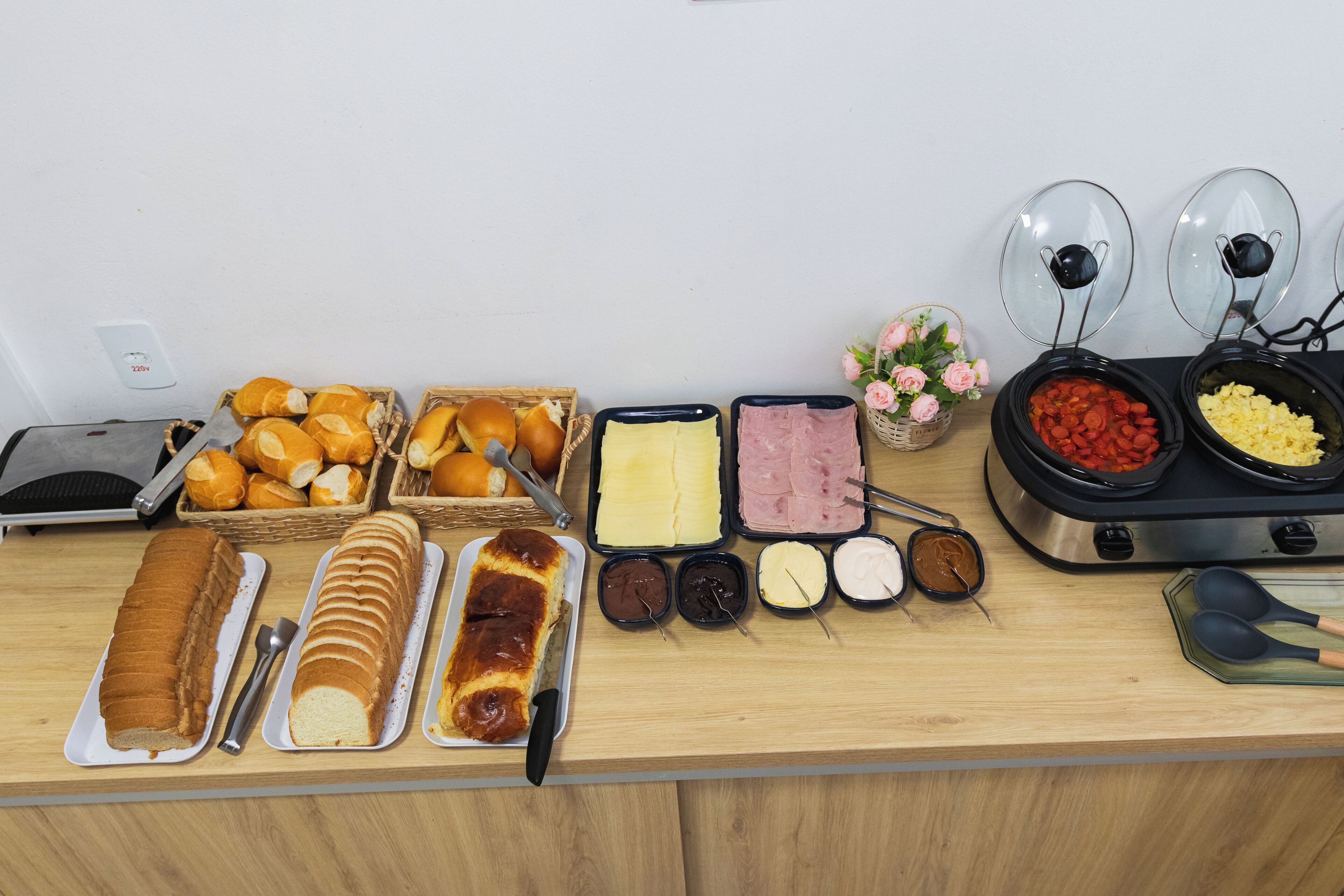 A buffet table with various food items including bread, pastries, and spreads.