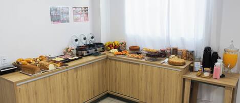 Una cocina con mostrador de madera que exhibe diversos productos para el desayuno, una cafetera y una frutera.