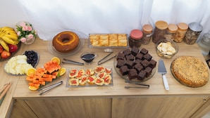 A buffet table with various food items including fruits, pastries, and desserts. - Pousada Paraná (Penha)