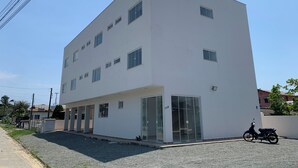 A modern building with a flat roof, multiple windows, and a covered entrance. - Pousada Paraná (Penha)