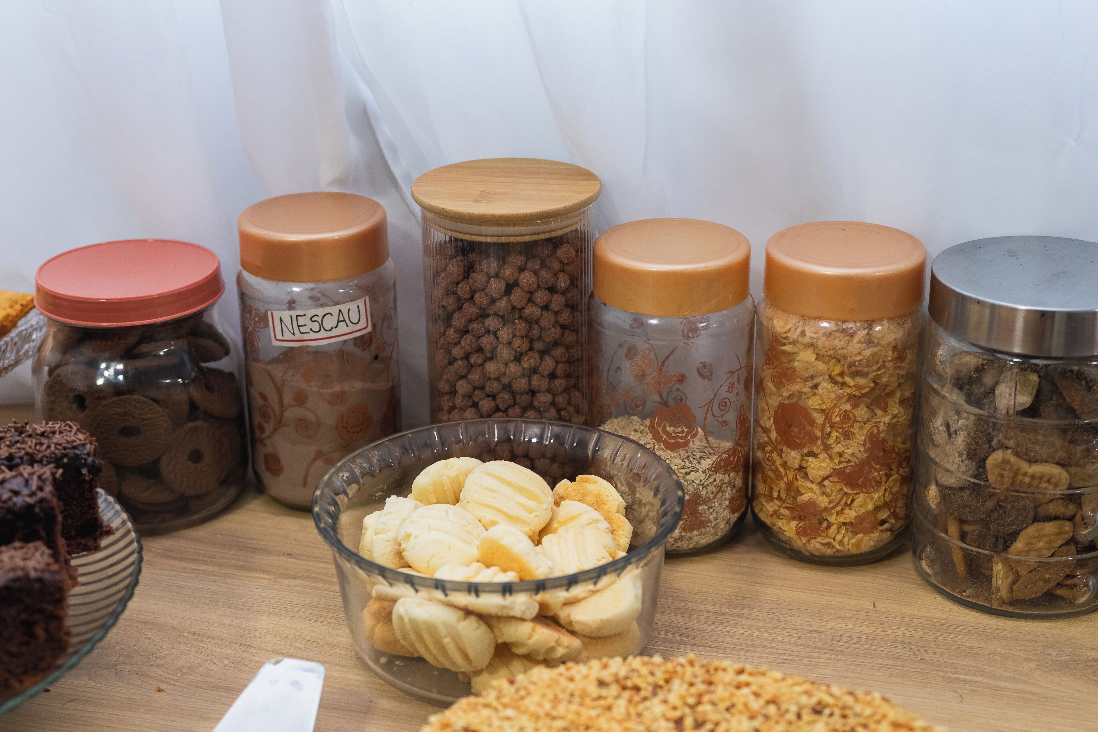 Diversos alimentos en frascos y un tazón sobre una mesa.