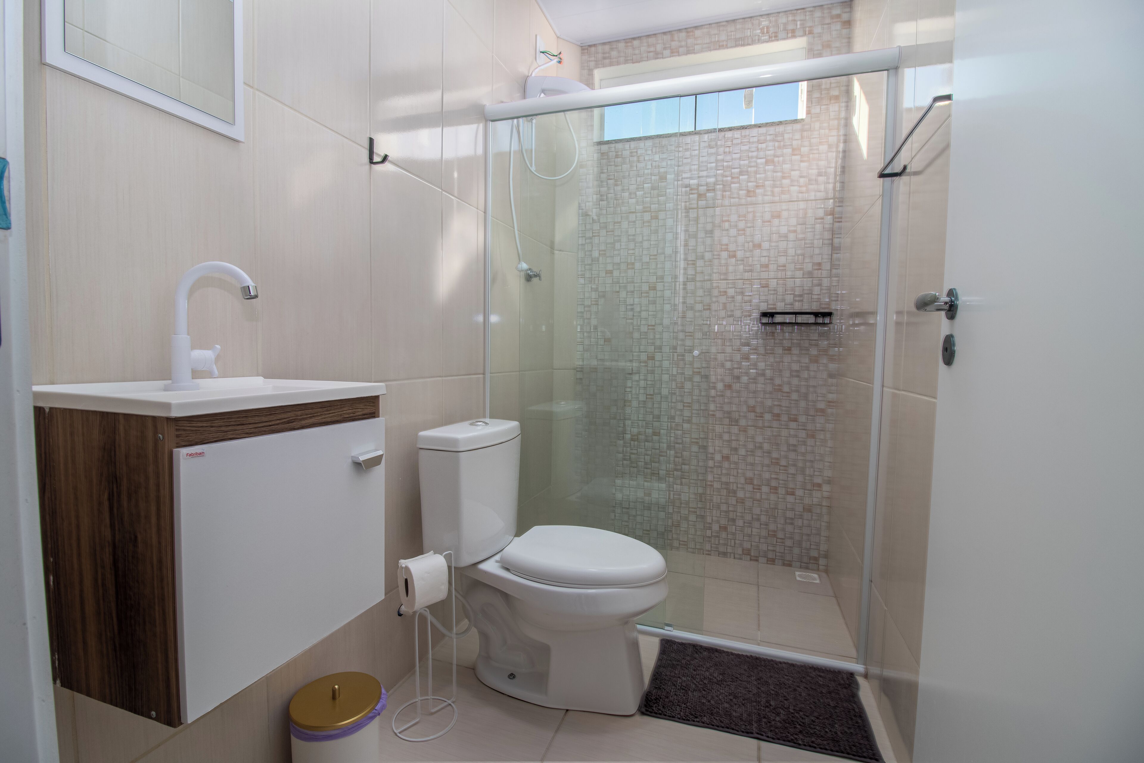 Un baño moderno con inodoro, lavamanos y ducha con mampara de vidrio.