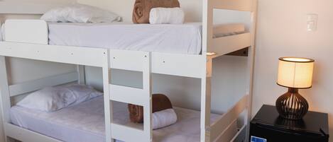 Habitación con literas, un escritorio pequeño y una lámpara.