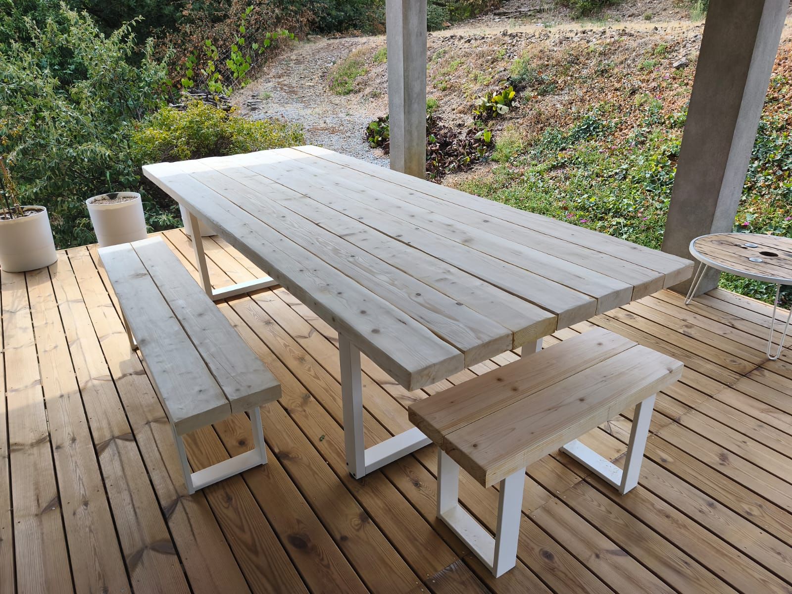 Een houten terras met een picknicktafel en banken.