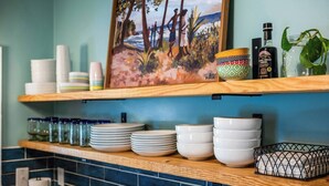 A kitchen counter with stacked white plates, a patterned bowl, and a bottle of organic vinegar.
