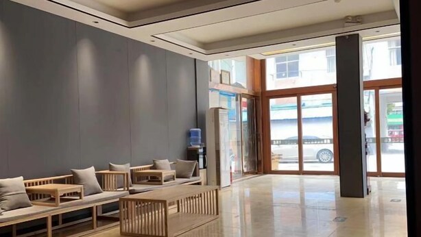 Un vestíbulo moderno con zonas de estar, una recepción y una puerta de cristal que da al exterior.