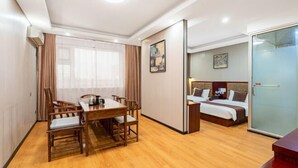 Una habitación de hotel con una mesa de comedor de madera, una cama con cabecera y un separador de vidrio.