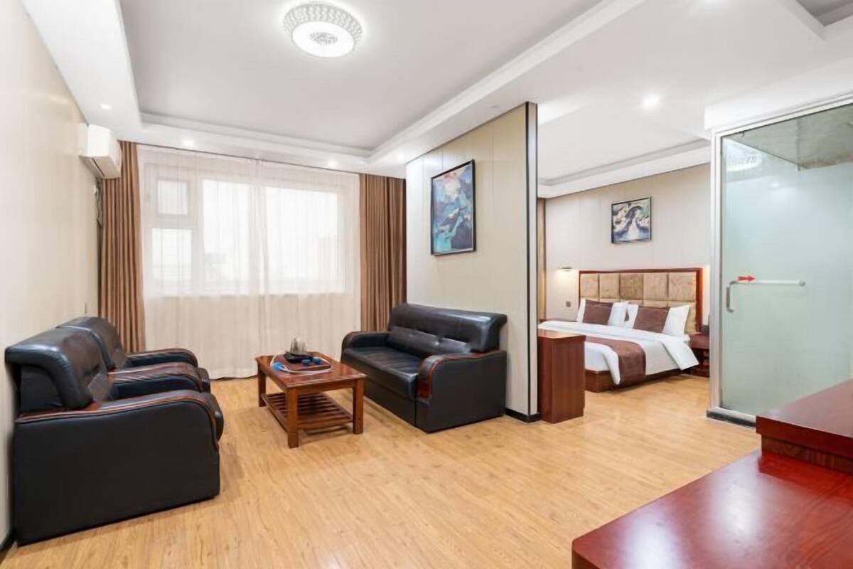 A hotel room with a bed, two sofas, a coffee table, and a desk.