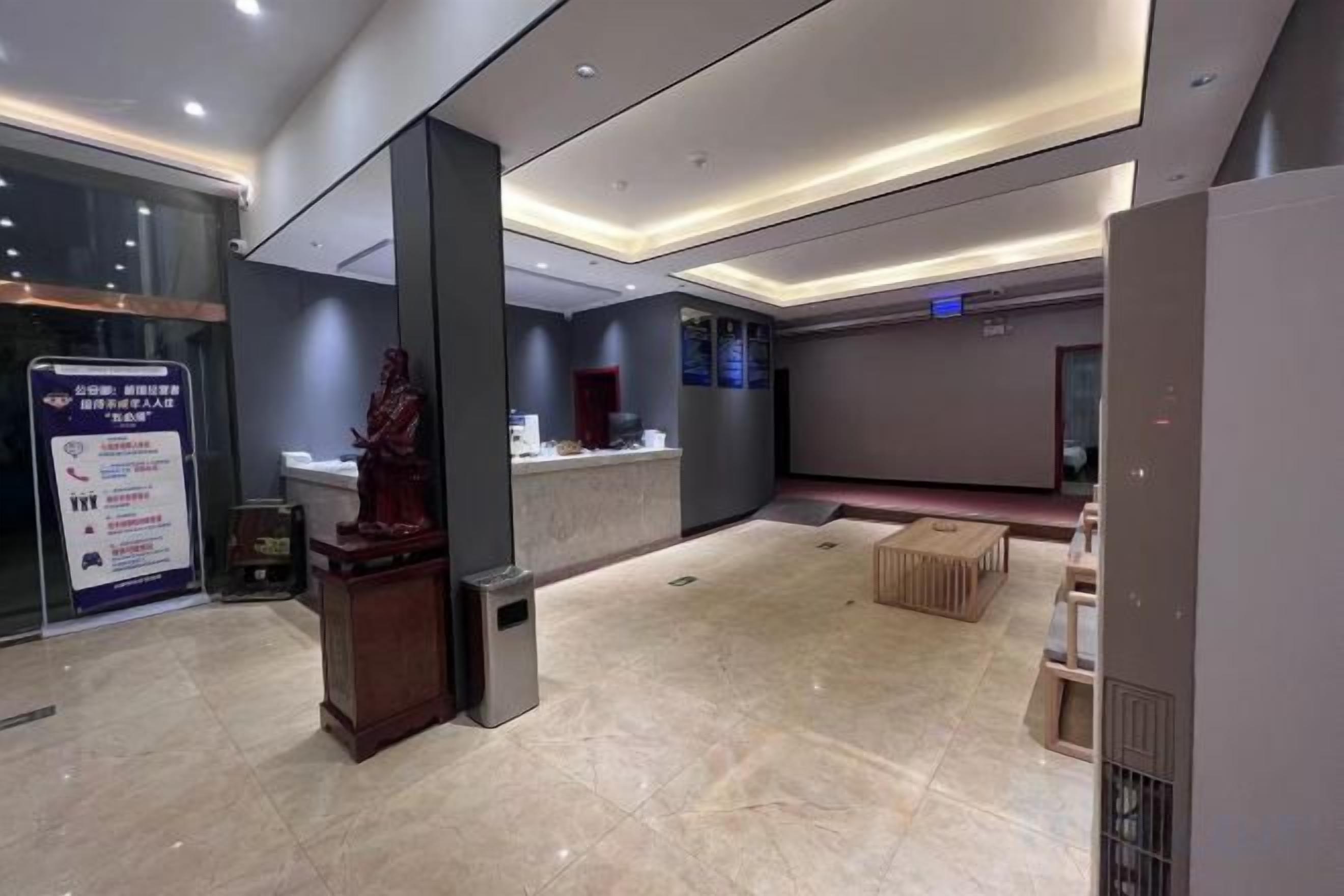 A modern hotel lobby with a reception desk, a statue, and a digital display.