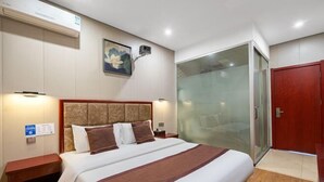 Habitación de hotel con una cama grande, una mesita de noche, aire acondicionado de pared, un cuadro y una puerta corredera de cristal.