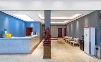 Zona de recepción con una estatua, un mostrador de recepción y un área de estar.