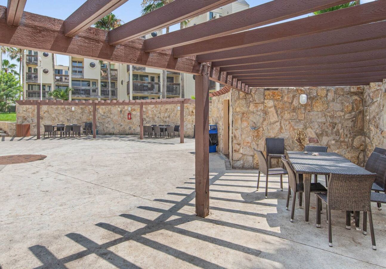 Une terrasse extérieure dotée d’une pergola, de murs en pierre et de mobilier d’extérieur.