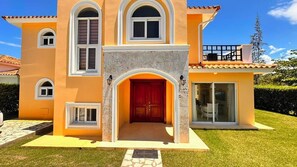 A two-story house with a red door, multiple windows, and a balcony. - Villa Giallo | Private Pool | Sosúa Ocean Village (Sosúa)