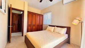 Een slaapkamer met een bed, een houten garderobe en een plafondventilator.