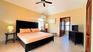 A bedroom with a bed, bedside tables, a ceiling fan, a TV, and a wardrobe. - Villa Giallo | Private Pool | Sosúa Ocean Village (Sosúa)